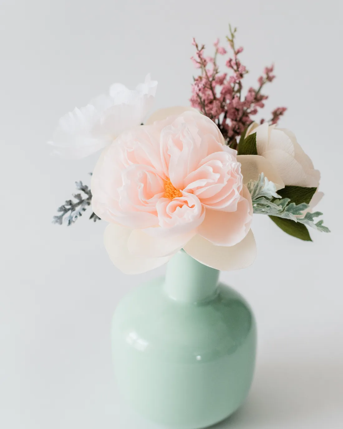 Pink paper peonies in a mint vase
